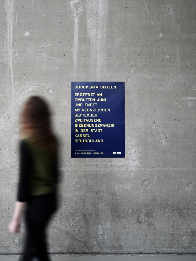 A woman is passing a D16 poster